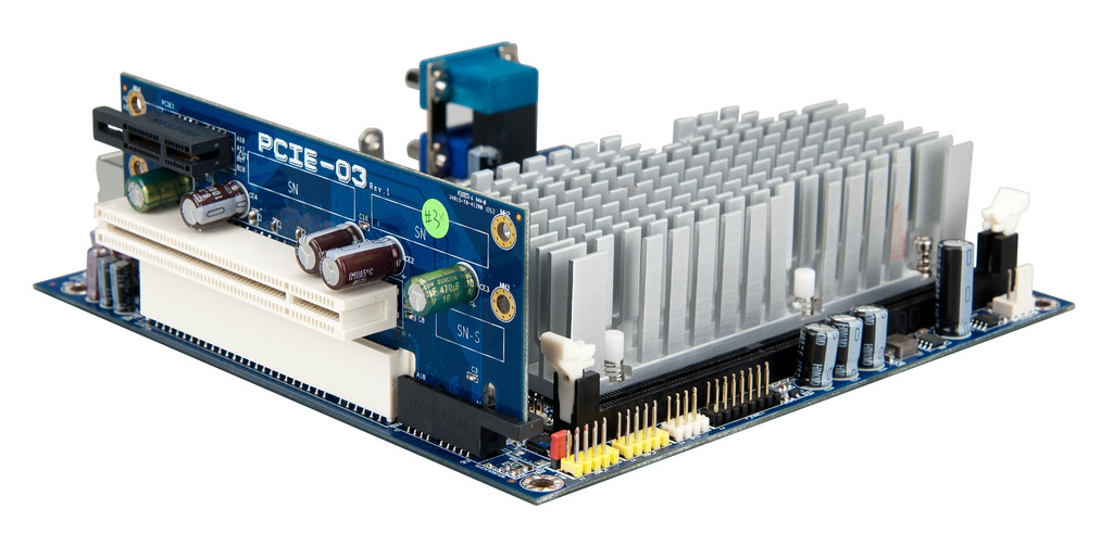 Photo of a small motherboard with a 2-slot PCIe riser card plugged
in